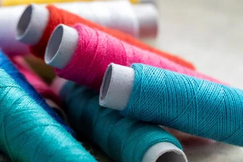 A portrait of three spools of colorful thread lying on some other rolls of fi Stock Photos