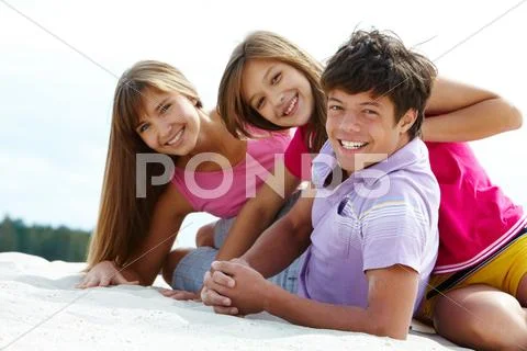 Portrait of three teenage friends on sandy beach Stock Photos