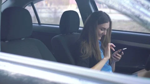 Portrait through the window of the girl using smartphone and smiling in car 4K Vídeo Stock 73806211