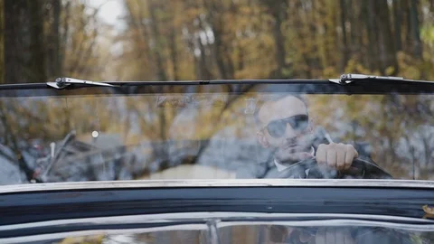 Portrait through windscreen of rich man in sunglasses sitting at handlebar Video stock 124731320