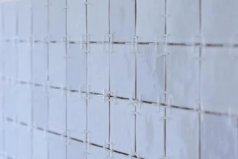 A portrait of a tile wall under construction. The wall is being tiled with .. Stock Photos