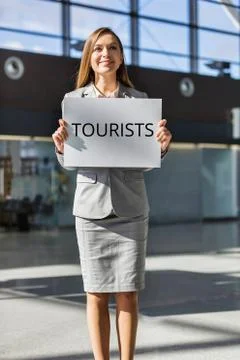 Portrait of tour operator standing while holding white board with TOURISTS si Stock Photos