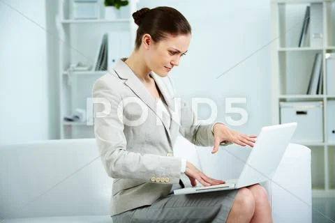Portrait of troubled businesswoman sitting in office and looking at laptop scree Stock Photos