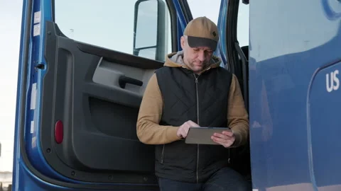 Portrait of truck driver . The driver uses a tablet computer Vidéo 223579247