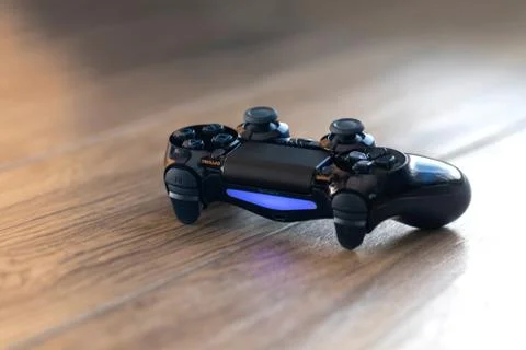 A portrait of a turned on Playstation 4 controller with a blue light indicati Stock Photos