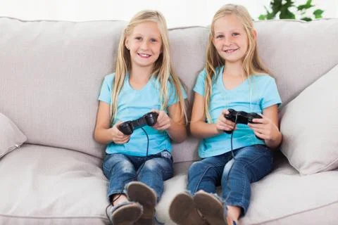 Portrait of twins playing video games together Stock Photos