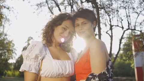 Portrait of two attractive women looking at camera smiling in front of sun rays Stock Footage