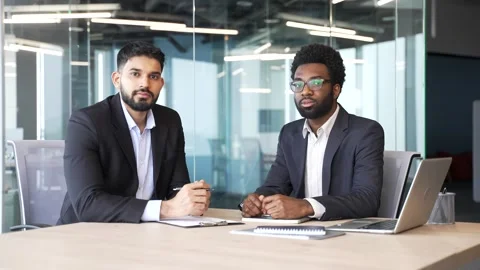 Portrait of two businessmen in suits sitting at office desk with serious Stock Footage 329052012
