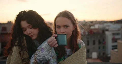 Portrait of two charming mixed race female friends wrapped in cozy plaid Stock Footage 125309902