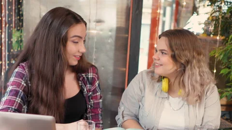 Portrait of two cheerful girlfriends talking in a cafe sharing their study notes Video stock 148332820