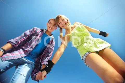 Portrait of two cheerful teenagers viewed from below against clear blue sky Stock Photos