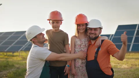 Portrait of two dads and two kids in protective helmets at a solar power plant Video stock 160956713