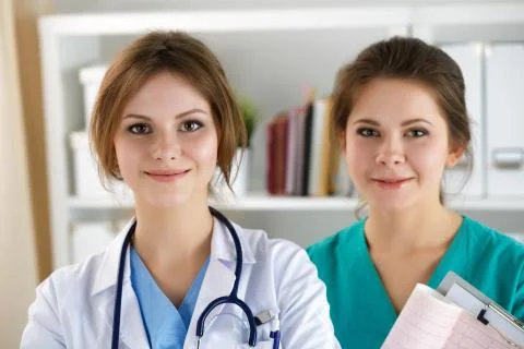 Portrait of two doctors standing at reception meeting patients Stock Photos
