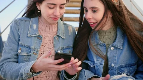 Portrait of two emotional young Hispanic sisters, stare at smart phone screen Stock Footage 106194565