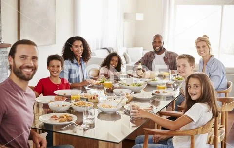 Portrait Of Two Families As They Enjoy Meal At Home Together Stock Photos