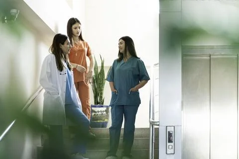 Portrait of two female doctors using mobile phone in corridor at hospital Stock Photos