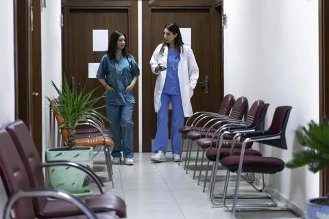 Portrait of two female doctors using mobile phone in corridor at hospital Stock Photos