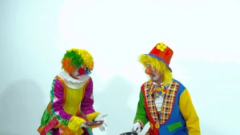 Portrait of two funny clowns playing with pans and false-cakes Видео 70514601