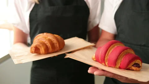 Portrait of two good looking young smiled male female bakers posing, croissants Stock-Footage 143747954