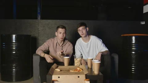 Portrait of two guys which eating popcorn during watching sport game on tv and Stock Footage 136340410
