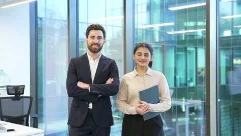 Portrait of two happy co-workers, a man and a woman standing in a modern glass  Stock Footage 298996588