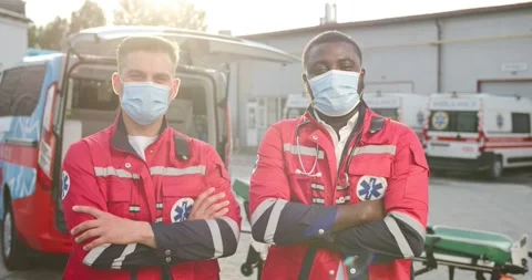 Portrait of two mixed-races young males paramedics in uniforms and masks 스톡 동영상 158316319