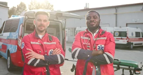 Portrait of two mixed-races young friendly males paramedics in uniforms standing Video stock 158316605