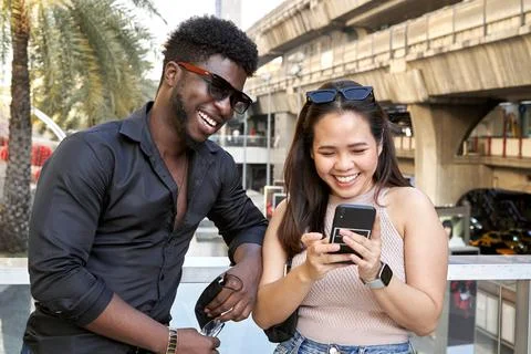 Portrait of two multiethnic friends using the mobile in a shopping mall Stock Photos