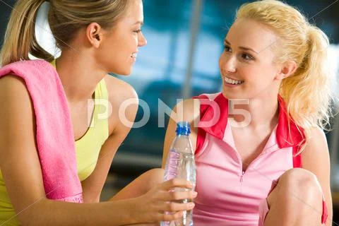Portrait of two pretty friends having a chat during workout in gym Stock Photos