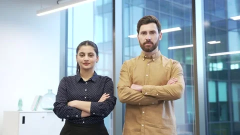 Portrait of two serious co-workers man and woman standing in modern glass office Stock Footage 298998335