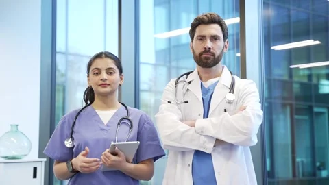Portrait of two serious doctors man and woman standing in hospital clinic look Stock Footage 298996294