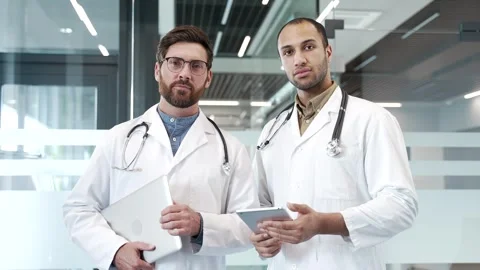 Portrait of two serious doctors standing in modern hospital clinic looking  Stock Footage 303413164