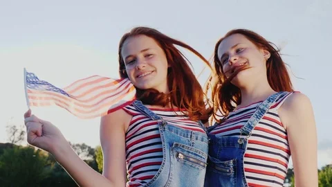 Portrait of two sisters of twins with the American flag. 4K slow motion video Stock Footage