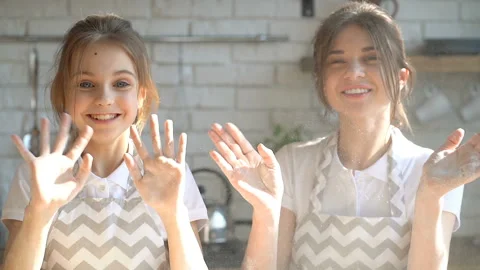 Portrait of two sisters. Waving hands, smiling and looking at camera. Stock Footage 105871153