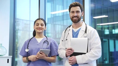 Portrait of two smiling doctors man and woman standing in hospital clinic look Video stock 309011168