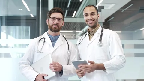 Portrait of two smiling doctors standing in modern hospital clinic looking  Stock Footage 309644383