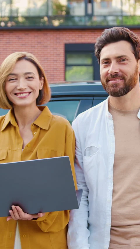 Portrait of two smiling people, man and woman, holding a laptop and posing in fr Stock Footage 327546295