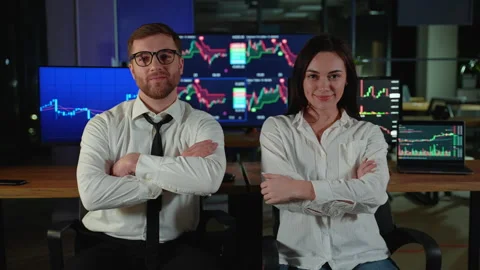 Portrait of two traders brokers in dark office. In the background monitors show Stock Footage 266465617