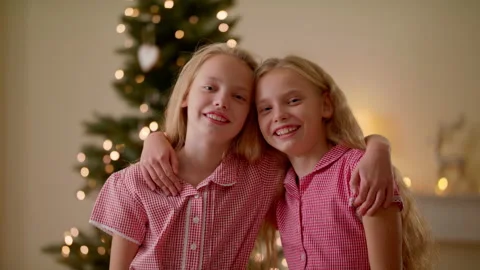 Portrait Of Two Twin Sisters Hugging And Smiling Near Christmas Tree Stock Footage 143047751