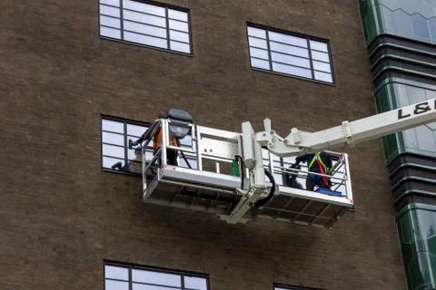 A portrait of two window washers, using a crane to get to the top windows of  Stock Photos