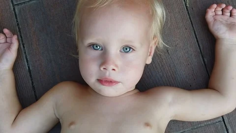  portrait of a two-year-old blond boy lying on the floor. Stock Footage 107859953