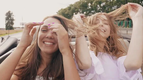Portrait of two young beautiful and smiling hipster girls in convertible car Stock Footage 146108201