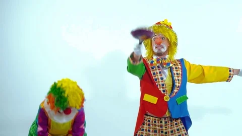 Portrait of two young comic clowns having fun together playing with toy-pans Видео 70515353