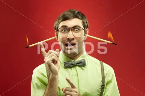 Portrait of typical nerd with burning sticks in his ears having an idea Stock Photos