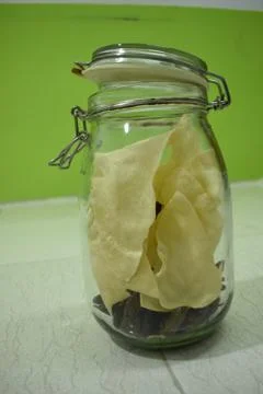 Portrait view a transparent jar inside fry poppadum in green and white backgr Stock Photos