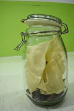 Portrait view a transparent jar inside fry poppadum in green and white backgr Stock Photos
