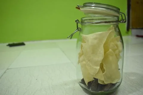 Portrait view a transparent jar inside fry poppadum in green and white backgr Stock Photos