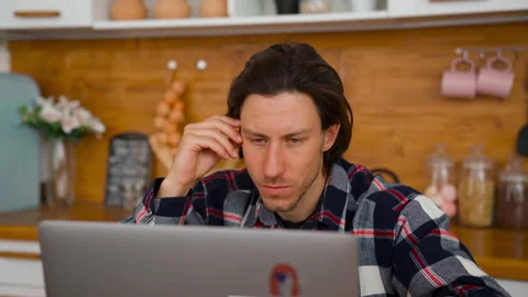 Portrait view: A young man working from home at the notebook in kitchen room. Stock Footage 137973271