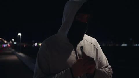 Portrait walking thief or robber in a mask hiding his face from cameras and a Stock Footage 249534553