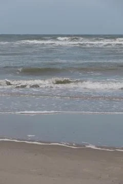 Portrait of waves breaking onto a sandy beach Stock Photos